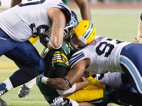 Toronto Argonauts' Cleyon Laing (90) and Ivan Brown (97) hit Edmonton Eskimos quarterback Mike Reilly (13) during first half action in Edmonton, Alta., on Saturday September 28, 2013. Reilly sustained a helmet-to-helmet hit on this play and was diagnosed with a concussion.