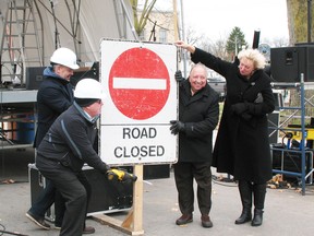 Mayor John McCharles uses a power saw to cut through a support post for a road closed sign at the official grand opening of Petrolia Line after two years of construction. Supporting the sign are, from left, Petrolia CAO Manny Baron, MPP Bob Bailey and MP Marilyn Gladu. (Don Robinet/Postmedia Network)