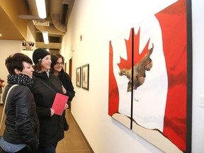 Hillory Speck, Lisa Marcon and Christine Vincent Van Belle check out a acrylic on birch painting by Susan Dalton at the Steelworkers Hall on Sunday. Gallery 6500 opened its newest exhibit Oh Canada? on Sunday afternoon. (Gino Donato/Sudbury Star)