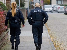 Policewomen walk along a street in Hameln, Germany, Monday Nov. 21, 2016. A woman was seriously injured when she was dragged Sunday through the streets of the northern German town behind a car with a cord tied around her neck. Her ex-partner later turned himself in to authorities, prosecutors said Monday, (Julian Stratenschulte/dpa via AP)