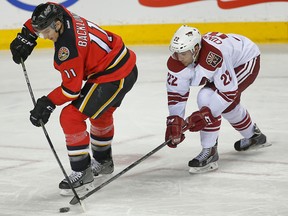 Calgary Flames Mikael Backlund battle for a loose puck against Craig Cunningham of the Arizona Coyotes during NHL hockey in Calgary on April 7, 2015. (Al Charest/Calgary Sun)