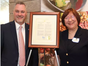 Deputy Mayor Mark Taylor with Ottawa Quota Club president Willy Lee, alongside an official Quota International of Ottawa Day proclamation from Mayor Jim Watson, at the service club's 70th anniversary celebration dinner, held at Algonquin College's Restaurant International on Monday, June 27, 2016. (Caroline Phillips, Postmedia)