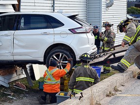 Firefighters and tow truck staff try to remove an SUV that became airborne and crashed through the wall of a woodworking shop in Collingwood Nov. 11. Witnesses say the driver was backing up when she brushed into a pedestrian who called out. The driver put the car back into drive and crashed through the wall. The only occupant of the building was in another part of the shop when the crashed occurred. The driver was taken to hospital for observation. Collingwood/Blue Mountain OPP investigated.
J.T. MCVEIGH/Postmedia Network