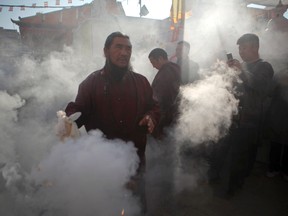 In this Nov. 20, 2016 file photo, a Buddhist monk swings an incense burner as other Buddhists gather during the final day of the three-days purification ceremony of Boudhanath Stupa in Kathmandu, Nepal. (AP Photo/Niranjan Shrestha, File)