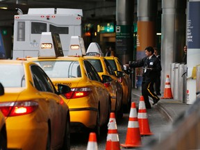 In this Wednesday, May 4, 2016, photo, a taxi dispatcher hands a piece of paper to a driver as other taxis line up awaiting passengers outside the arrivals area of a terminal at LaGuardia Airport, in New York. (AP Photo/Kathy Willens)
