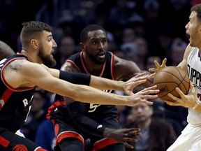 Los Angeles Clippers forward Blake Griffin, right, controls the ball in front of Toronto Raptors center Jonas Valanciunas, left, of Lithuania, and forward Patrick Patterson, center, during the second half of an NBA basketball game in Los Angeles, Monday, Nov. 21, 2016. (AP Photo/Alex Gallardo)