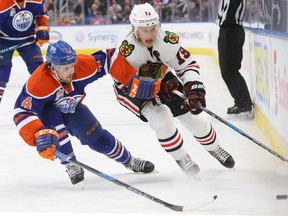 Kris Russell and Jonathan Toews battle for the puck during Monday's game at Rogers Place. (The Canadian Press)