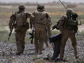 Canadian soldiers help a comrade, center, get on a helicopter after he was injured in an IED blast during a patrol outside Salavat, in the Panjwayi district, southwest of Kandahar, Afghanistan, Monday, June 7, 2010. THE CANADIAN PRESS/AP/Anja Niedringhaus