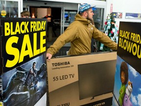 A customer carries a large TV to the checkout at a Best Buy store on Black Friday, shortly after the store’s 6 a.m. opening on Friday, Nov. 27, 2015 in Ottawa. (THE CANADIAN PRESS/Justin Tang)