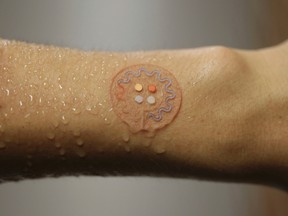 This photo provided by J. Rogers of Northwestern University shows a soft, skin-mounted microfluidic device for capture, collection and analysis of sweat. (J. Rogers, Northwestern University via AP)