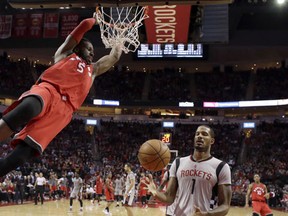 Toronto Raptors' DeMarre Carroll hangs from the rim after a dunk as Houston Rockets' Trevor Ariza reaches for the ball during the second half of an NBA basketball game Wednesday, Nov. 23, 2016, in Houston. (AP Photo/David J. Phillip)