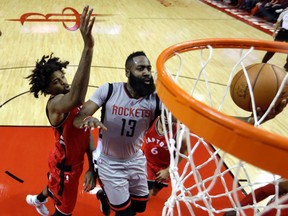 Rockets' James Harden (right) goes up for a shot as Raptors' Lucas Nogueira (left) defends during first quarter NBA action in Houstn on Wednesday, Nov. 23, 2016. (David J. Phillip/AP Photo)