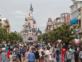 In this May 12, 2015, file photo, visitors walk near Sleeping Beauty's Castle at Disneyland Paris, in Marne la Vallee, east of Paris.  (AP Photo/Michel Euler, File)