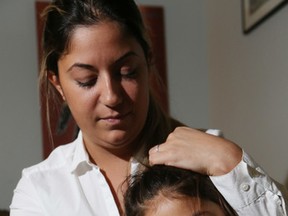 Melissa Dickemous and her six- year-old daughter Aiyanna on the couch with their cat, Fox. Aiyanna wandered off school grounds with a friend to visit her cat unbeknownst to the Holy Cross Catholic School on Nov. 24, 2016. (Stan Behal/Toronto Sun)