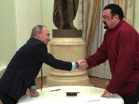 Russian President Vladimir Putin shakes hands with U.S. actor Steven Seagal in the Kremlin in Moscow,Friday, Nov. 25, 2016. Putin has given a Russian passport to Seagal, a regular visitor to Russia in recent years, calling it a sign of a thaw in relations between the two countries. (Alexei Druzhinin/Sputnik, Kremlin Pool Photo via AP)