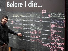 Downtown Association manager Josh Ingram takes his turn to write a message on the Before I Die Wall on Fri. Nov. 25, 2016.  The chalkboard has been installed in the alley between Queen and King streets to encourage urban expression and the important conversation about living life well.