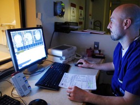 Technologist Jason Sangiuliano examines images from the MRI machine at Belleville General Hospital to scan patient Donald Postar in Belleville, Ont. Wednesday, March 23, 2016. Staff and doctors have cut wait times for scans dramatically, but the machine will soon need an upgrade if that service is to be maintained. 
Photo by Luke Hendry