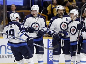Winnipeg Jets defenseman Dustin Byfuglien, center, is congratulated by teammates after scoring a goal against the Nashville Predators during the first period of an NHL hockey game Friday, Nov. 25, 2016, in Nashville, Tenn. The Jets face the challenge of snapping a losing streak on Sunday. (AP Photo/Mark Humphrey)