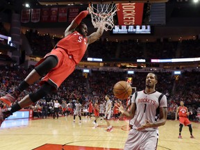 Toronto Raptors' DeMarre Carroll hangs from the rim after a dunk as Houston Rockets' Trevor Ariza reaches for the ball during the second half of an NBA game on Nov. 23, 2016, in Houston. (AP Photo/David J. Phillip)