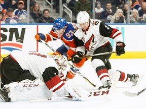 Ryan Nugent-Hopkins battles Coytes Luke Schenn as goaltender Mike Smith smothers the puck during Sunday's game at Rogers Place. (The Canadian Press)