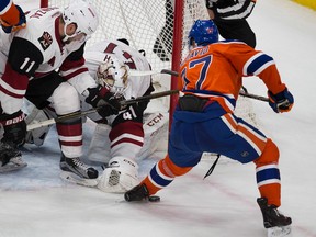 Coyotes goalie Mike Smith dives for the puck as Connor McDavid digs for it during Sunday's game at Rogers Place. (Greg Southam)