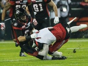 Ottawa Redblacks defensive back Antoine Pruneau (left) brings down a Calgary Stampeder during Grey Cup action at BMO Field in Toronto on Sunday night. The Redblacks upset the heavily favoured Stamps in overtime 39-33. (CRAIG ROBERTSON/POSTMEDIA NETWORK)