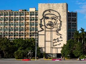 Tourists walk by the iconic image of Cuba's revolutionary hero Ernesto "Che" Guevara, at Revolution Square near the Ministry of Interior in Havana, Cuba, Sunday, Nov. 27, 2016. (AP Photo/Desmond Boylan)
