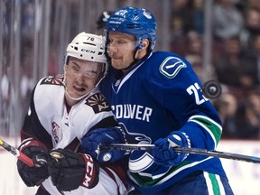 Vancouver Canucks defenceman Alexander Edler fights for control of the puck with Arizona Coyotes centre Laurent Dauphin during NHL action in Vancouver on Nov. 17, 2016. (THE CANADIAN PRESS/Jonathan Hayward)