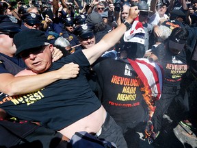 In this July 20, 2016 file photo, a law enforcement officer takes Gregory "Joey" Johnson into custody after he started to burn an American flag in Cleveland, during the third day of the Republican convention. President-elect Donald Trump said Tuesday that anyone who burns an American flag should face unspecified "consequences," such as jail or a loss of citizenship _ a move that was ruled out by the Supreme Court nearly three decades ago. (AP Photo/John Minchillo)