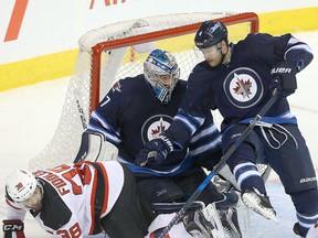 New Jersey Devils left winger Vernon Fiddler (l) and Winnipeg Jets defenceman Paul Postma fall over Jets goalie Connor Hellebuyck during NHL hockey in Winnipeg, Man. Tuesday November 29, 2016. The Jets defeated the Devils 3-2. Brian Donogh/Winnipeg Sun/Postmedia Networ