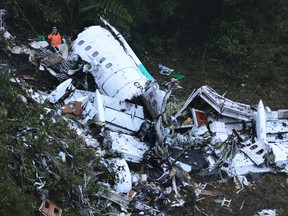 Rescue workers stand at the wreckage site of a chartered airplane that crashed in a mountainous area outside Medellin, Colombia, Tuesday, Nov. 29, 2016. The plane was carrying the Brazilian first division soccer club Chapecoense team that was on it's way for a Copa Sudamericana final match against Colombia's Atletico Nacional. (AP Photo/Luis Benavides)