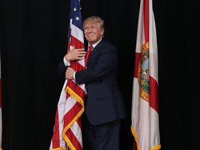 Donald Trump hugs the American flag as he arrives for a campaign rally at the MidFlorida Credit Union Amphitheatre on October 24, 2016 in Tampa. (Joe Raedle/Getty Images)