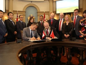 Roger Hua Liu, vice chairman and chief financial officer of Feihe International Inc., and Mayor Bryan Paterson sign an agreement at Kingston City Hall on December 1, 2016. Elliot Ferguson, Kingston Whig-Standard, Postmedia Network