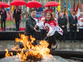Olympic speed skating star Catriona Le May Doan (right) and Patrick Kenny of the Canada Games light the Canada Winter Games torch on Parliament Hill in 2014. Ottawa is one of four cities chasing the summer version of the Games in 2021. (The Canadian Press)