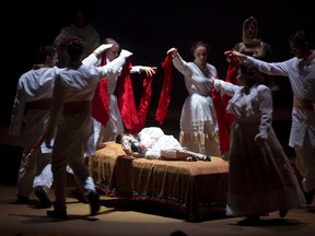 Lily, played by Charlotte Abbott, stares at a photograph in bed as cast members dance around her in a scene from the London Community Players? production of The Secret Garden. (Free Press file photo)