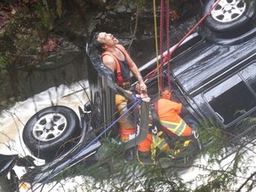Members of the Sechelt Fire Department work to free the driver of a vehicle that drove off the Sunshine Coast Highway near Madeira Park, B.C. on Wednesday, November 23, 2016. THE CANADIAN PRESS/ HO, RCMP