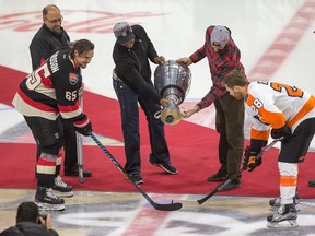 Redblacks’ Henry Burris and Brad Sinopoli drop the puck from the Grey Cup for the ceremonial faceoff before the Senators took on the Flyers last night. (WAYNE CUDDINGTON/Postmedia Network)