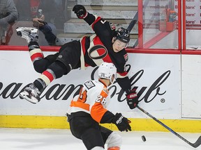 Senators’ Curtis Lazar is upended while Flyers forward Claude Giroux looks on during last night’s game at the CTC. (WAYNE CUDDINGTON/Postmedia Network)