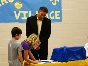 Leea Carmichael and Kelton Granley sign the affirmation of citizenship as Parkland County Mayor Rod Shaigec looks on during the Parkland Village School’s MicroSociety ceremony on Nov. 24 - Photo by Marcia Love.