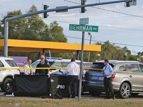 The body of CFL player Joe McKnight lies between the shooter's vehicle, at left, and his Audi SUV at right as the Jefferson Parish Sheriff's Office investigates the scene in Terrytown, La., Thursday, Dec. 1, 2016. (Michael DeMocker /NOLA.com The Times-Picayune via AP)
