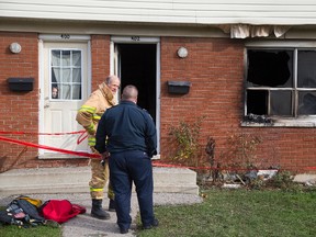 A child peeks out the window as investigators examine the scene of a fire in the townhouse next door at 402 Boullee St. in London, Ont. on Tuesday November 29, 2016. (DEREK RUTTAN, The London Free Press)