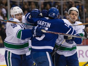 Maple Leafs left wing Matt Martin (15) gets roughed up by Canucks centre Brendan Gaunce (50) and right wing Jake Virtanen (18) during NHL action in Toronto on Nov. 5, 2016. (Craig Robertson/Toronto Sun)