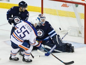 Winnipeg Jets goaltender Michael Hutchinson (34) stops the shot from Edmonton Oilers' Mark Letestu (55) as Jets' Toby Enstrom (39) defends during third period NHL action in Winnipeg on Thursday, December 1, 2016.