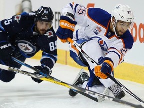 Winnipeg Jets forward Mathieu Perreault (85) goes down as Edmonton Oilers' Darnell Nurse (25) clears the puck during second period NHL action in Winnipeg on Thursday, December 1, 2016.
