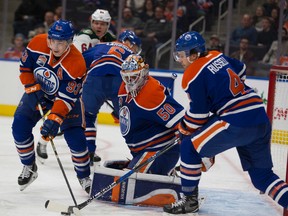 Ryan Nugent-Hopkins, left and Kris Russell work to move the puck away after goaltendter Jonas Gustavsson stops a shot during Sunday's game at Rogers Place. (Greg Southam)