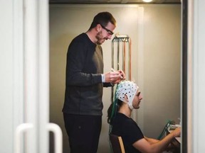Researcher Kyle Mathewson and master's student Sayeed Kizuk demonstrate the use of EEG technology for studying information processing in the brain.