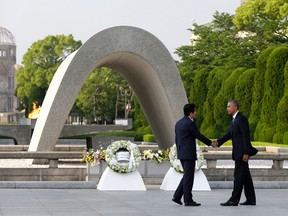 In this May 27, 2016 file photo, U.S. President Barack Obama, right, shakes hands with Japanese Prime Minister Shinzo Abe at Hiroshima Peace Memorial Park in Hiroshima, western Japan, as Obama became the first sitting U.S. president to visit the site of the world's first atomic bomb attack. Abe said Monday, Dec. 5, he will visit Pearl Harbor with Obama at the end of this month, becoming the first leader of his country to go to the U.S. Naval base in Hawaii that Japan attacked in 1941, propelling the United States into World War II. Atomic Bomb Dome is seen in the background. (AP Photo/Carolyn Kaster, File)