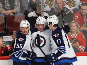 Winnipeg Jets Andrew Copp (middle), Marko Dano (left) and Adam Lowry (right) and the rest of the team are going to have to get used to their road whites for a while -- they play their next four of their next six games away from home. (AP Photo/Kamil Krzaczynski)