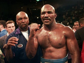 In this Nov. 9, 1996, file photo, Evander Holyfield raises his fist after defeating Mike Tyson in their WBA heavyweight championship bout at the MGM Grand Garden in Las Vegas. (AP Photo/ Mark J. Terrill, File)