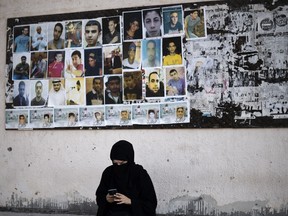A Bahraini woman sits near portraits of jailed political activists and protesters killed during clashes with police, before taking part in a demonstration to mark the fifth anniversary of the Arab Spring-inspired uprising in the mainly Shiite village of Sitra, south of Manama, on February 12, 2016. (MOHAMMED AL-SHAIKH/AFP/Getty Images)
